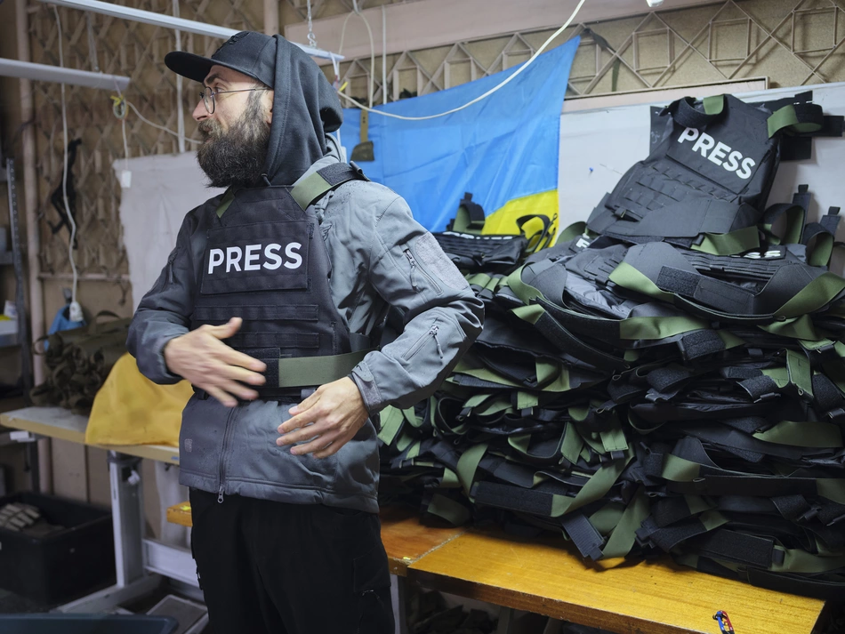 Informazioni sicure in Ucraina Un uomo con un giubbotto “stampa” è in piedi davanti a un mucchio di materiale - protezione per coloro che informano la popolazione durante la guerra in Ucraina.