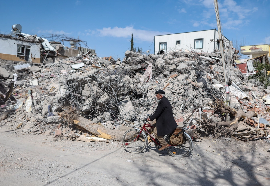 Aiuti di emergenza dopo il terremoto in Turchia In Turchia, un uomo in bicicletta passa davanti agli edifici distrutti dal terremoto - necessità di aiuti d'emergenza, ricostruzione e sostegno a lungo termine