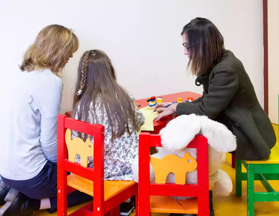 Due donne accompagnano un bambino in uno spazio protetto: un sostegno essenziale per i bambini vulnerabili, che unisce protezione, aiuto duraturo e ascolto.