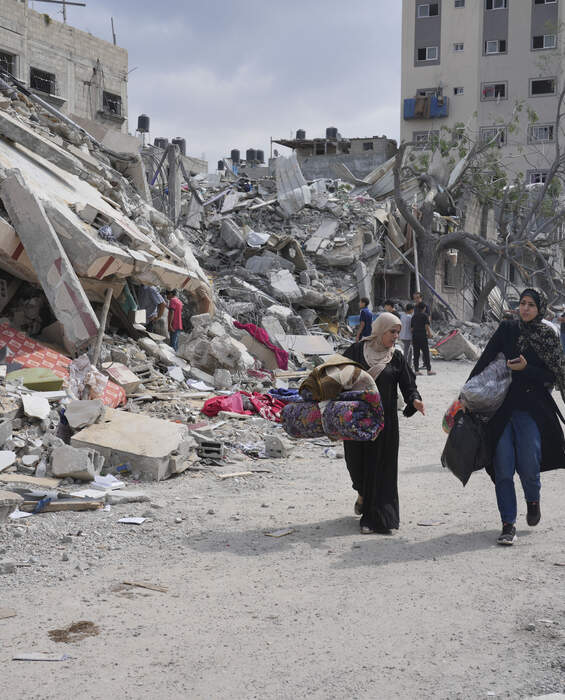 Distruzione a Gaza - richiesta urgente di aiuti Donne palestinesi camminano davanti agli edifici distrutti di Nuseirat, Gaza - urgente bisogno di aiuti umanitari.
