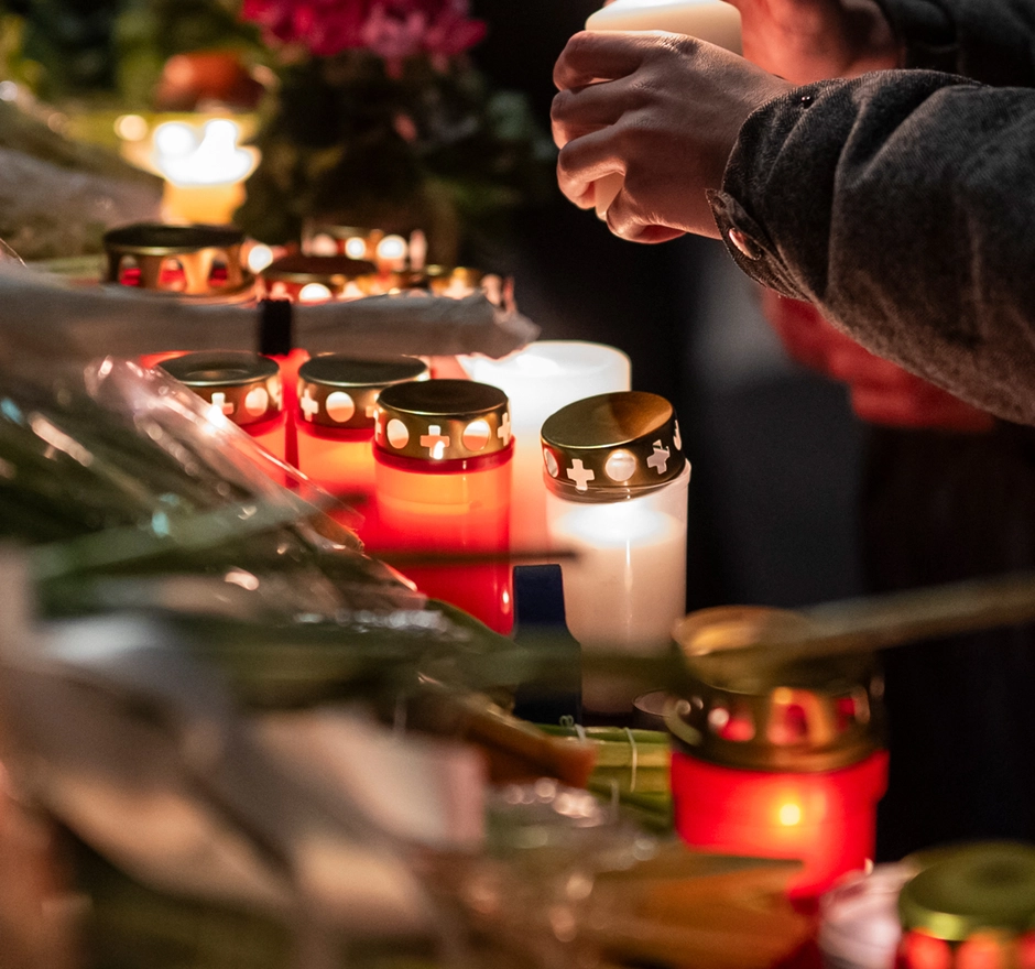Una persona accende delle candele per un altare funebre.