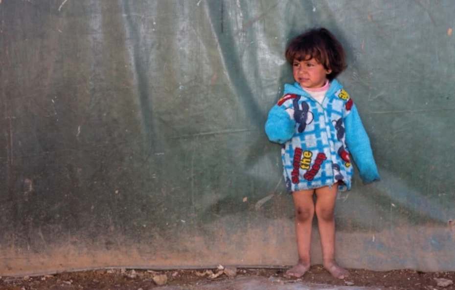 Bambina a piedi nudi su terra battuta con sguardo ansioso – dona ora per aiutare i bambini in difficoltà.