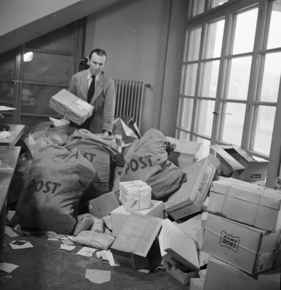 Un uomo ordina grandi sacchi di lettere e pacchi – segno del primo impegno internazionale della Catena della Solidarietà dopo la guerra.